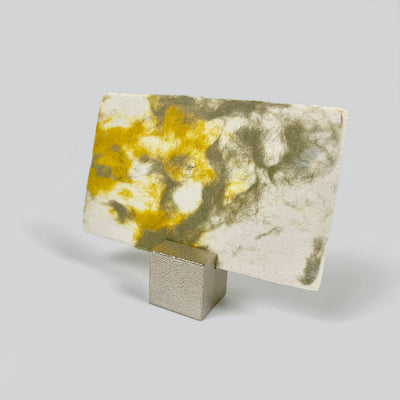 Brass cube card holder holding a yellow and gray marbled card. The card is the size of a business card.
