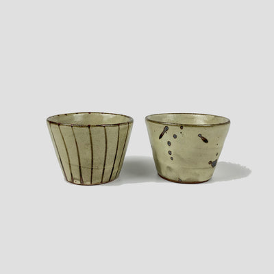 Ceramic cups with line pattern on the left and splash pattern on the right.