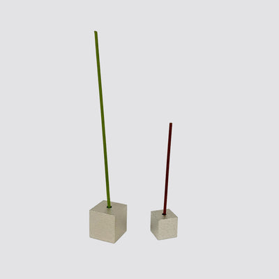 A large silver brass cube incense holder with a green incense stick on the left and a small silver brass cube incense holder with a brown incense stick on the right.