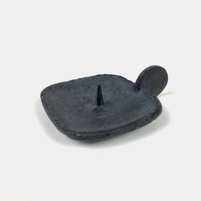 Close-up of a cast iron candle holder with handle.