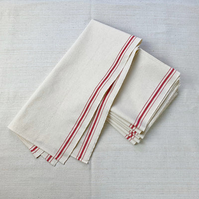 A gently folded cotton dish cloth over a stack of folded cotton dish cloths.